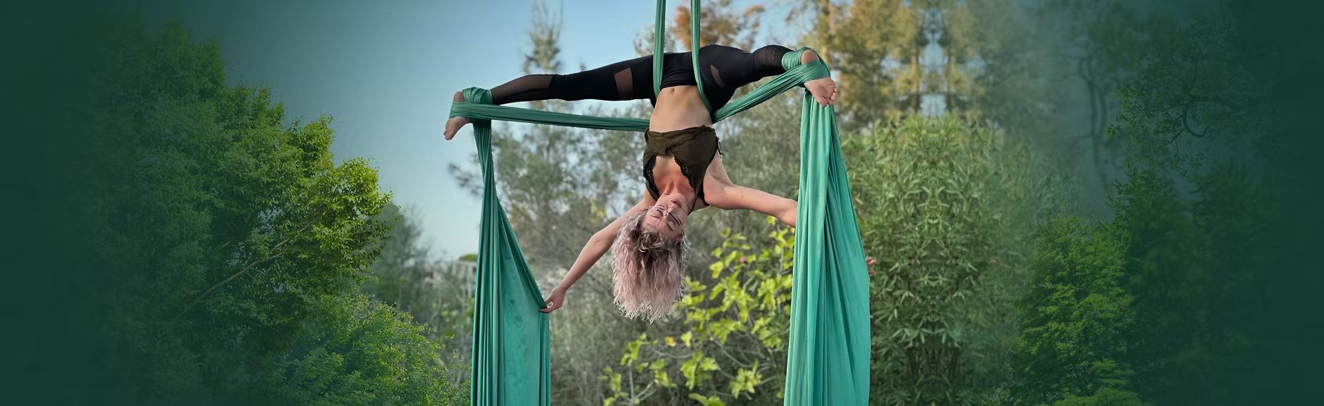 Meredith in an inverted split on green silks among the garden trees
