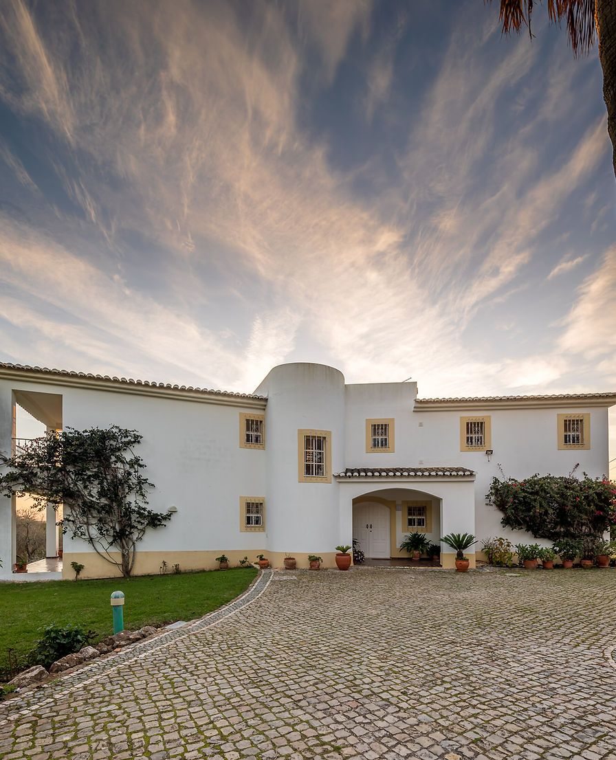 Casa de Campo, a white villa with a cobbled drive under a dramatic sky