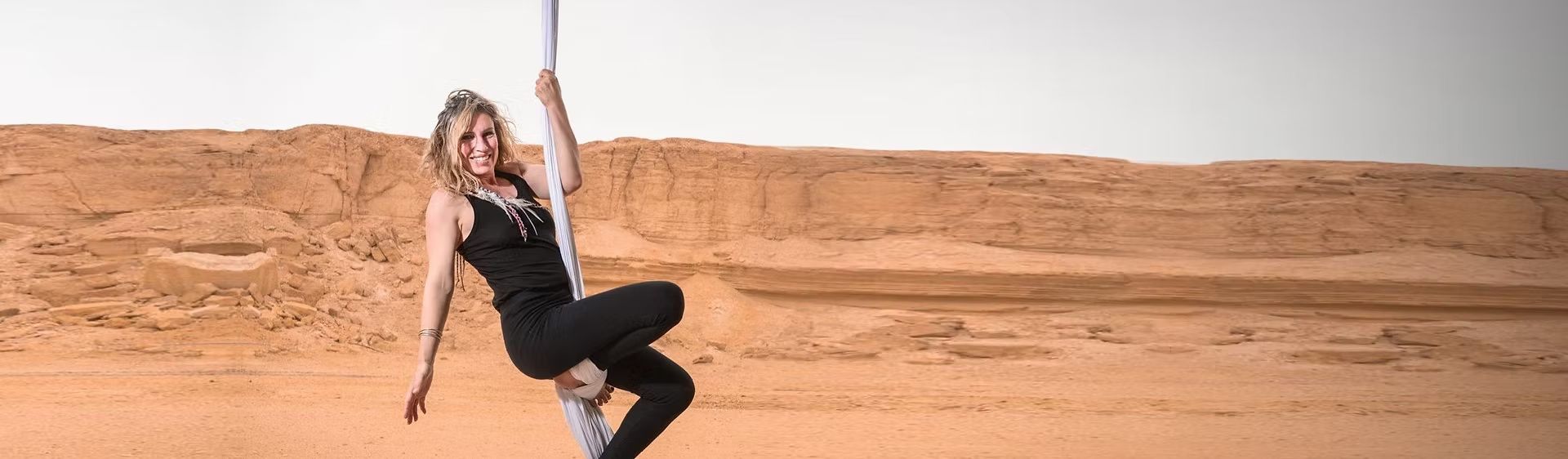 Aerialist on silks in front of desert cliffs