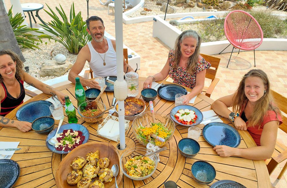 Retreat guests smiling around a table of shared dishes