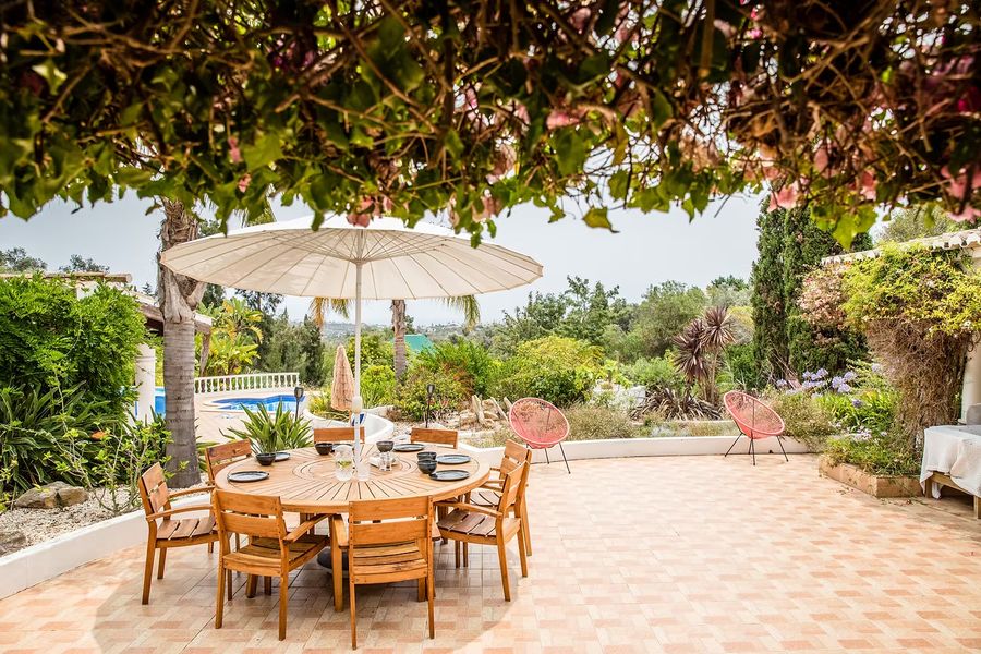 Outdoor dining table under a parasol on the villa terrace