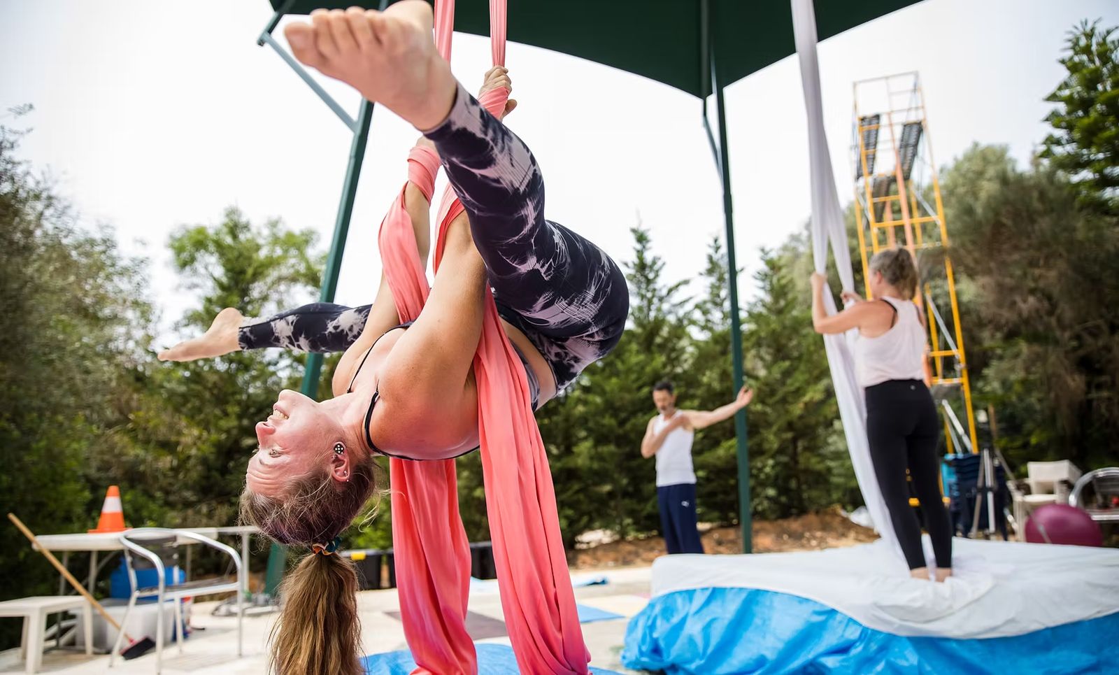 Aerialist inverted in pink silks under the studio canopy