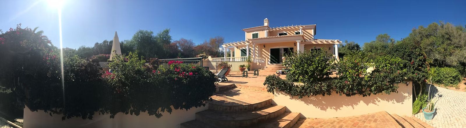 The villa and its terraced garden under a blue sky