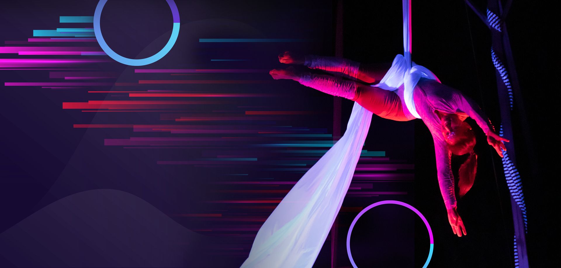Aerialist on white silks under pink and purple stage light