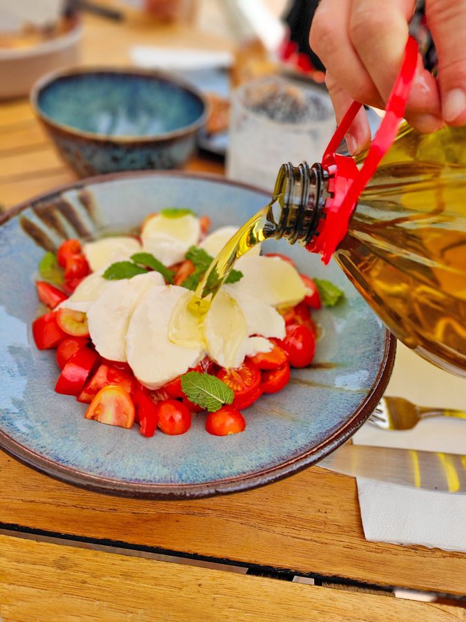 Olive oil poured over tomato and mozzarella salad
