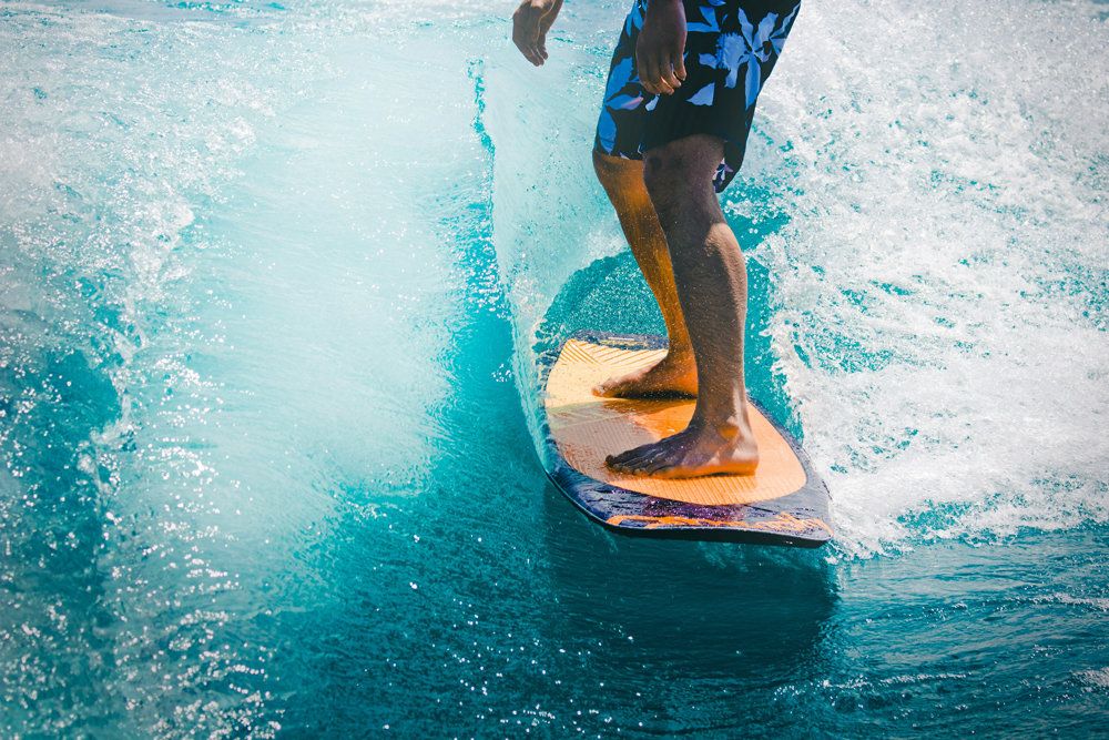 A surfer’s feet on a board riding a turquoise wave